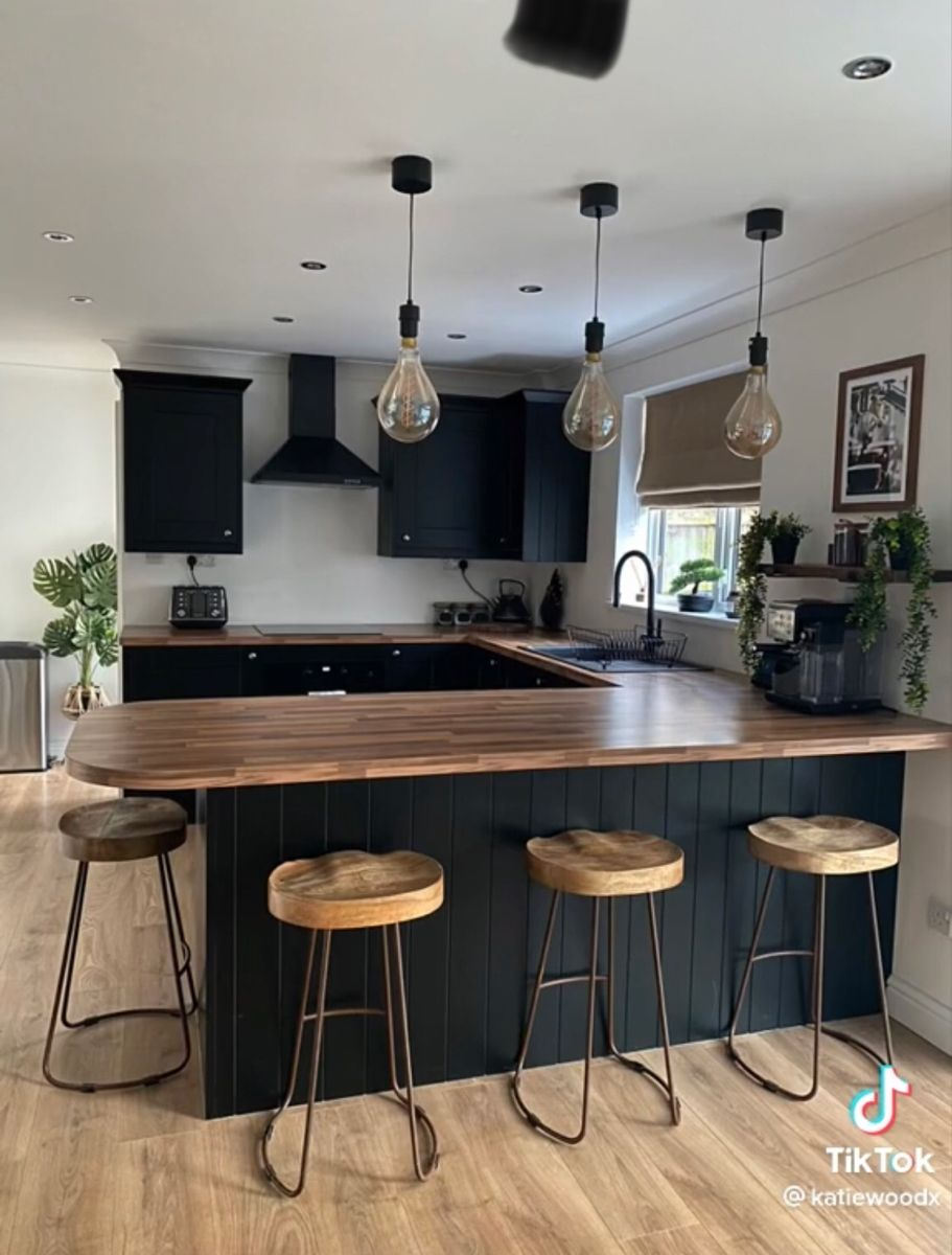 Dark matte kitchen with wood countertops and pendant lights